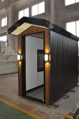 Compact black factory display cabin with gable roof and lit entrance